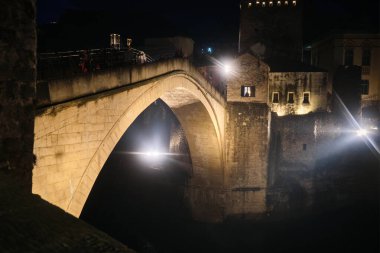 Büyük taş kemer köprüsü sıcak mimari aydınlatmayla çarpıcı bir şekilde aydınlatıldı. Bosna-Hersek 'in Mostar kentindeki eski köprü. UNESCO Dünya Mirası