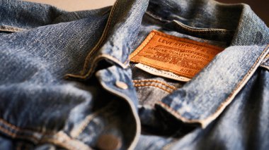 Mavi kot pantolon Levi Strauss kamyoncu ceketinin yakından görüntüsü kumaş ve dikiş detaylarını gösteriyor. Eski kot kumaşının eskimiş, engebeli görünüşü