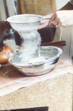 Kadınların elleri elek tutuyor ve un elemek