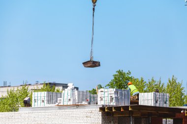 Tuğla ev inşaatı. Vinç yük düşürür