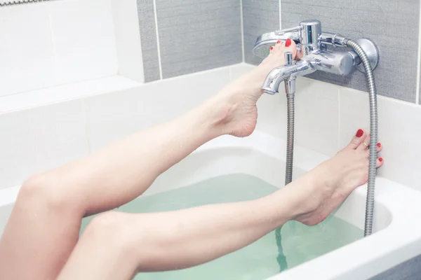 Kvinnliga fötter med pedikyr i badet med vatten — Stockfoto