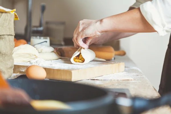 Las manos femeninas sujetan las mitades del pastel con el relleno — Foto de Stock