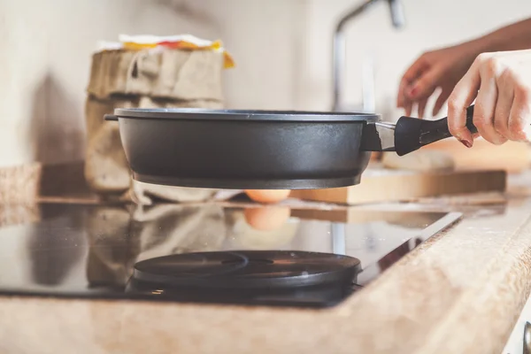 Женская рука кладет сковороду на плиту — стоковое фото