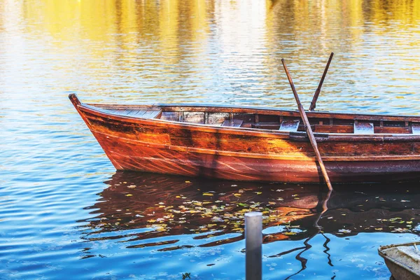 Wooden boat reflected in water of pond — Stock Photo, Image