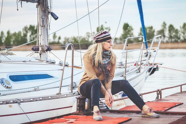 Cute blonde sitting in front of yacht. — Stock Photo, Image