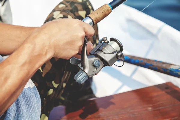 Die Hände des Fischers, der Angelrute und Spulengriff hält, werden gedreht — Stockfoto