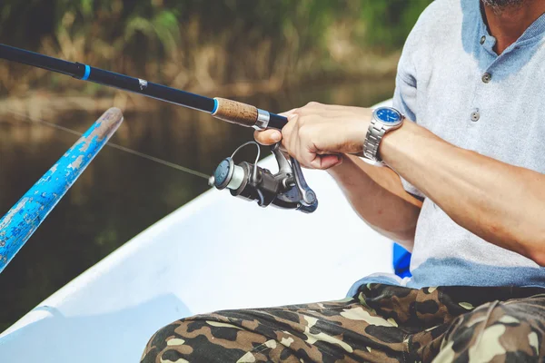 Hands fisherman holding fishing rod and reel handle is rotated — Stock Photo, Image