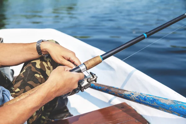 Die Hände des Fischers, der Angelrute und Spulengriff hält, werden gedreht — Stockfoto