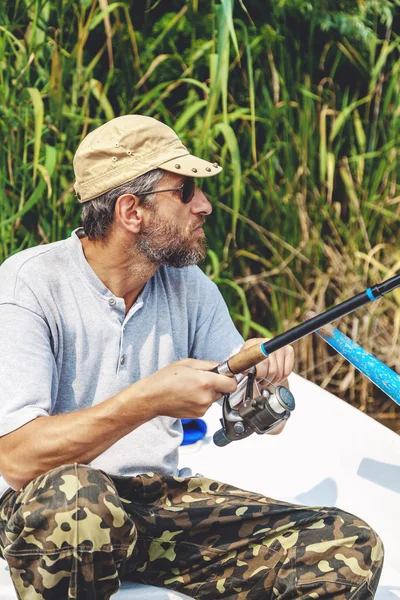 髭のボートに座っていると、釣り竿を持って漁師 — ストック写真