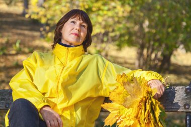 Sonbahar parkta bankta oturan çekici yaşlı kadın