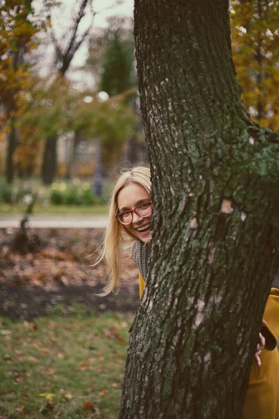 Good Mood Pretty Blonde Glasses Smiles Looks Out Tree Trunk — Stock Photo, Image
