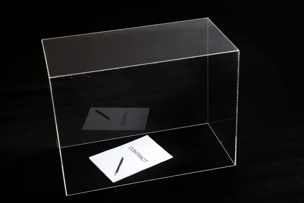 contract is under control. A contract printed on paper and a pen lies in a glass box