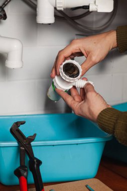 Su tesisatının elleri mutfak hidrolik deklanşör sistemini söküyor. Boru anahtarının yanında.