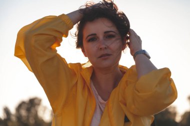 Uzun kızıl saçlı, parlak sarı ceketli, uzun boylu, güzel bir kızın portresi.