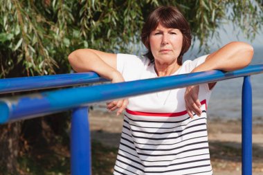 Nehir kıyısında jimnastik. Sevimli yaşlı kadın metal barda sağlık egzersizleri yapıyor.