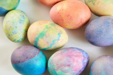 Paskalya tatiline özen göster. Farklı renklerde boyanmış birkaç tavuk yumurtası beyaz bir sırt grubunda.