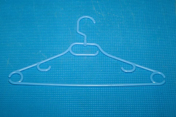 Plastic clothes hanger lies on a blue background in a small cag