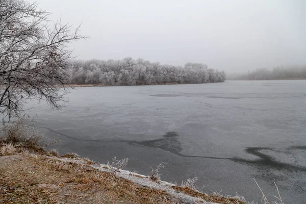 crack on a frozen river. The surface of the river is covered with ice. There is a big crack on the ice. Gray fog above the ic