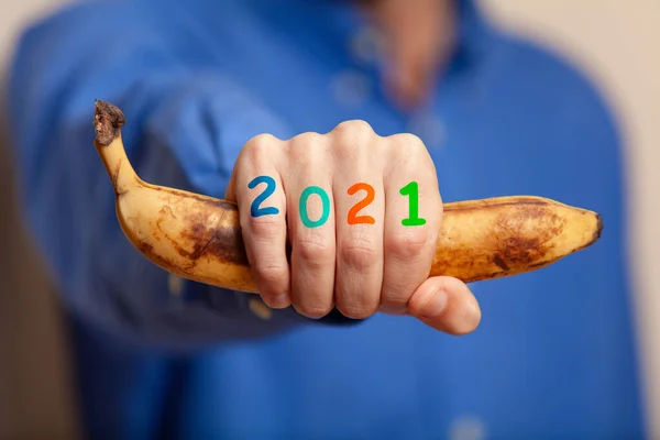 2021 Мужская Рука Голубой Рубашке Сжимает Спелый Банан Кулаке Номера — стоковое фото
