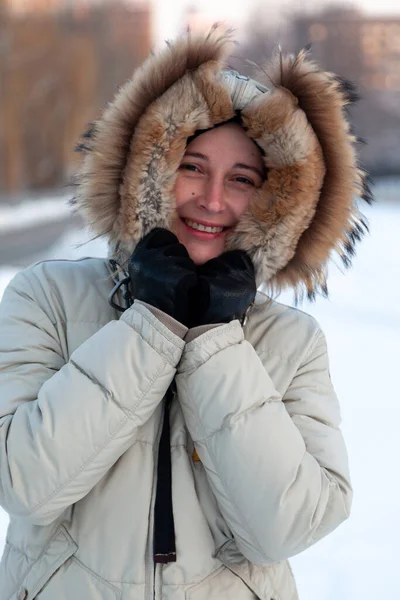 頭にフード付きの薄手のジャケットを着た美しい若い女性が冬の通りに立っています 自然な不完全さに触れずに女性の肖像画 — ストック写真