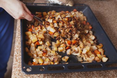 İştah açıcı sebze güveci. Büyük çelik kaşık fırında pişirilmiş sebzeleri karıştırır.