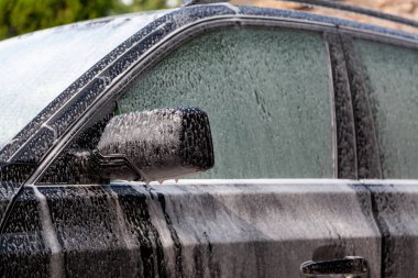 Araba yıkama. Arabanın gövdesi tamamen beyaz deterjan köpüğüyle kaplıydı.