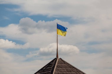 Ukrayna 'nın sarı-mavi ulusal bayrağı bulutlu bir gökyüzüne karşı kahverengi bir çatıda bayrak direğinde dalgalanıyor