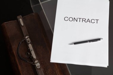 Açık arttırmada sözleşme. Kağıda basılmış bir sözleşme ve deri bir halı torbası. Kalem kontrastın üstünde.