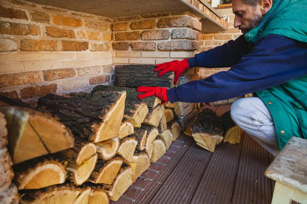 man in red work gloves neatly stacks a log of mulberry tree with a yellow core in a brick nich