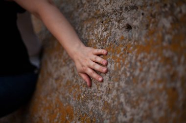 Taşın üzerinde zarif bir el. Sol kadın eli eski bir taş levhanın üzerinde yatıyor. Sarı noktalar ston üzerinde görünür.