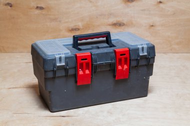 Modern plastik kapalı alet kutusu hafif bir kontrplak arka grubuna karşı duruyor