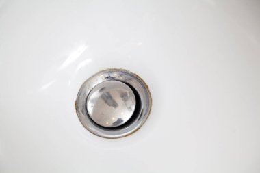 Beyaz bir küvetin dibinde yuvarlak metal su boşaltımı var.