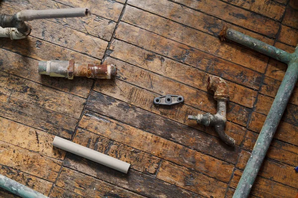旧金属水管和水龙头的碎片躺在旧木地板上 Abov的观点 — 图库照片