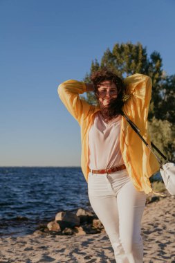 Su yüzeyinin arka planında uzun kızıl saçlı, uzun boylu güzel bir kız duruyor. Doğal kusurlarıyla rötuş yapmayan bir kadının portresi