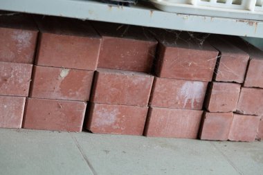 Seramik fayans üzerine istiflenmiş üç sıra yeni kırmızı tuğla.