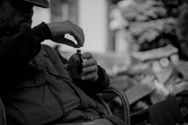 Oturan ve içinde alkol olan metal bir matarayı açan adamın silueti.