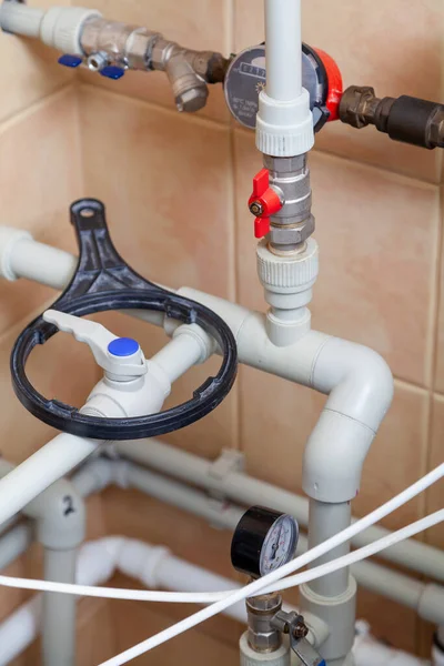 system of gray plastic plumbing pipes. Above is a special black round wrench for dismantling the water filter housin