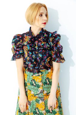 Kısa saçlı, kısa kollu bluzlu, beyaz bir sırt grubunda şık sarışın.