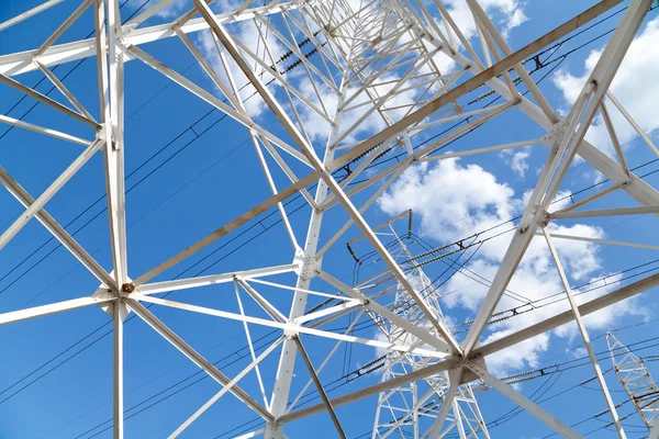 Visão inferior linhas de transmissão de energia contra o céu azul — Fotografia de Stock