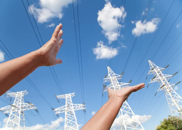 Hands reach for power transmission lines against blue sky — Stock Photo, Image