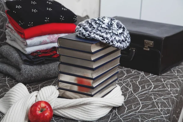 Stack of winter clothes and books with glossy edge