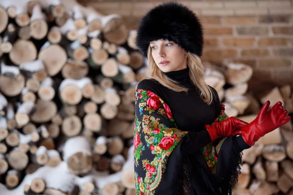 Winter portrait of the girl on a background firewood — Stock Photo, Image