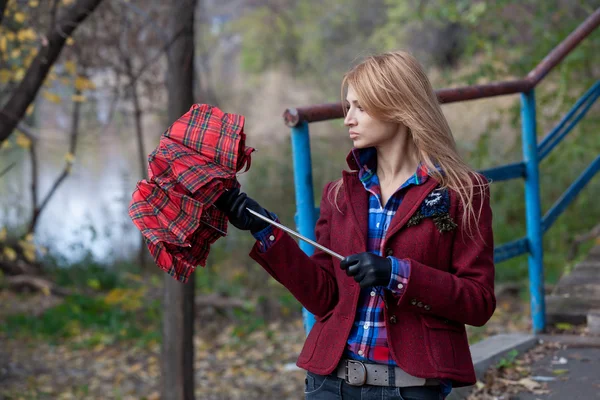 Elegante rubia en chaqueta roja abre paraguas — Foto de Stock