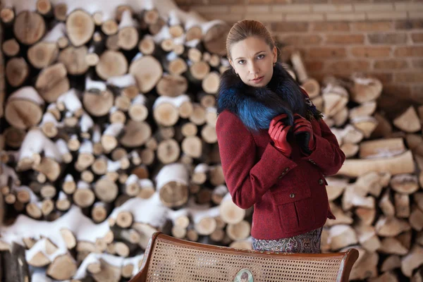 Retrato de invierno de mujer rubia sobre fondo de leña — Foto de Stock