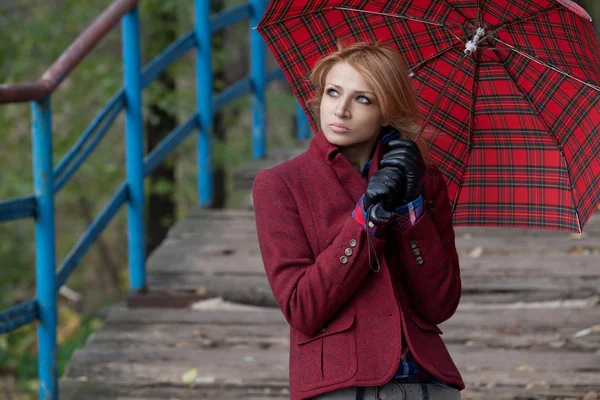 Attractive blonde woman posing under a red umbrella