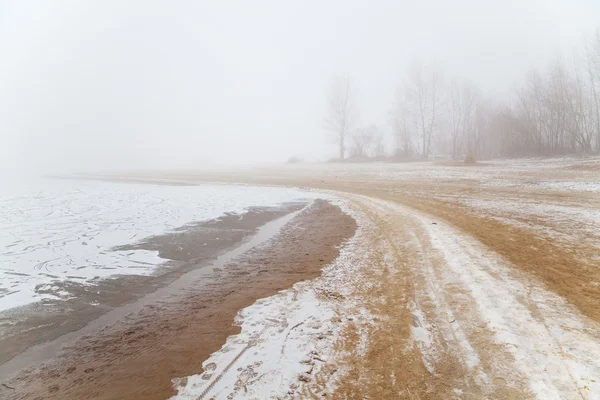 Sandy beach by the river in the fog in winter — Stock Photo, Image