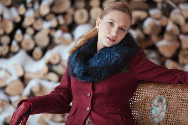 Winter portret van blonde vrouw op brandhout achtergrond — Stockfoto