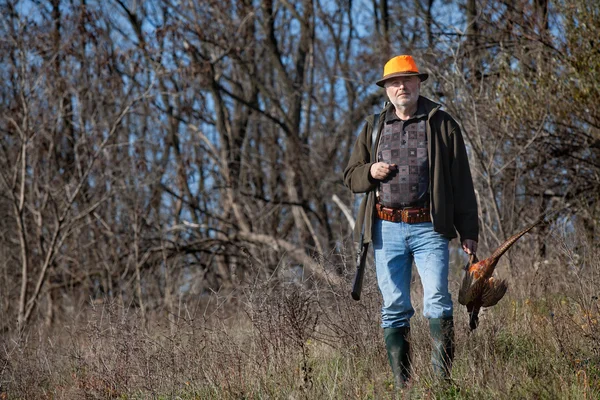 Elderly hunter with wildfowl in orange hat — Stock Photo, Image