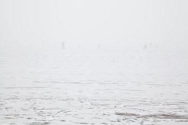 Donmuş nehir üzerinde siste balıkçıların siluetleri