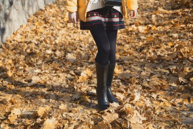 Sonbahar sarı yapraklar üzerinde yürüme düzgün kadın bacakları